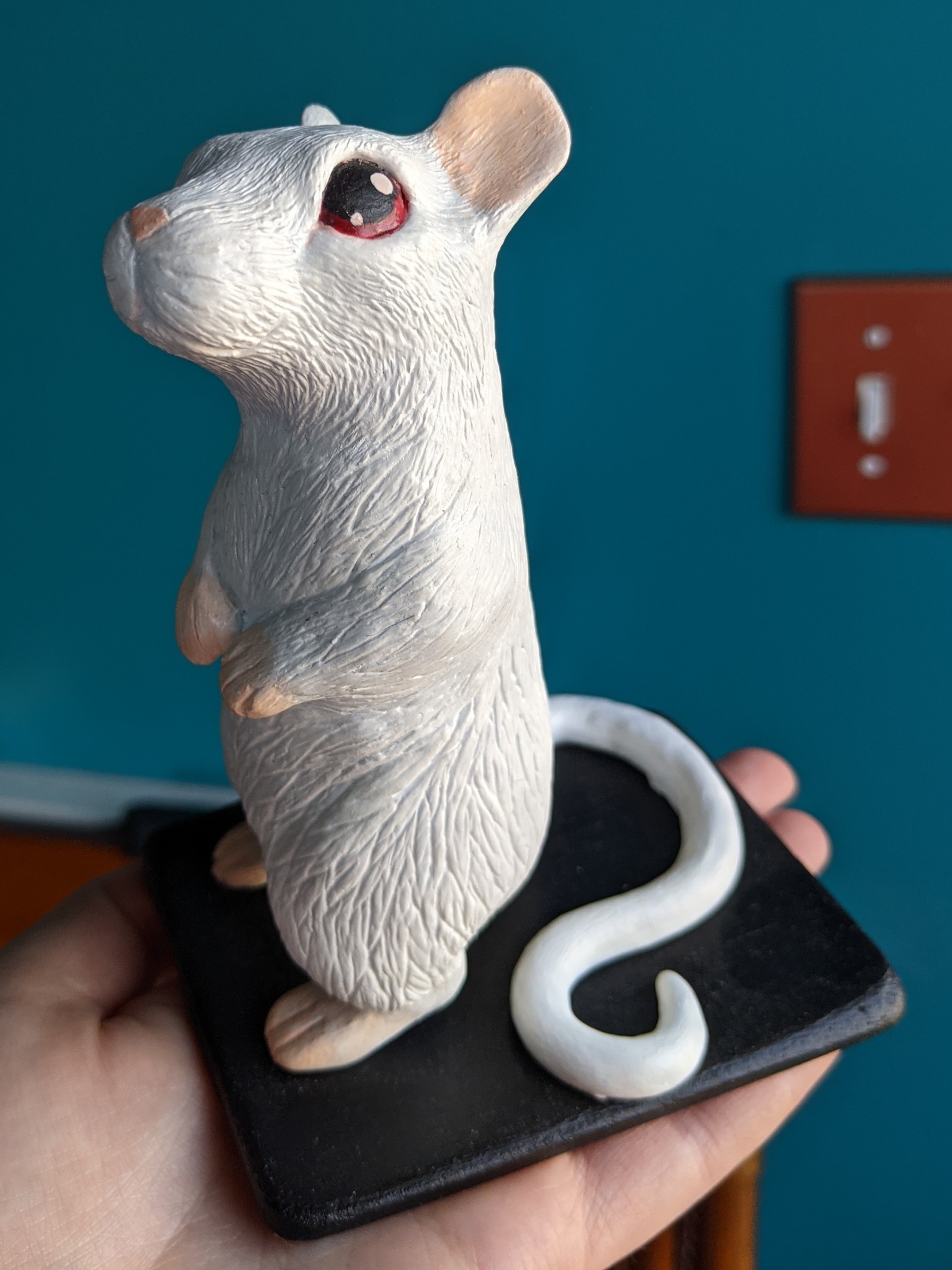 Sculpture of a white gerbil with red eyes standing on its hind legs